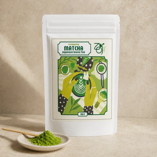 Matcha ceremonialna ZOI w białej saszetce 100 g, przed nią talerzyk z proszkiem i bambusowa łyżeczka